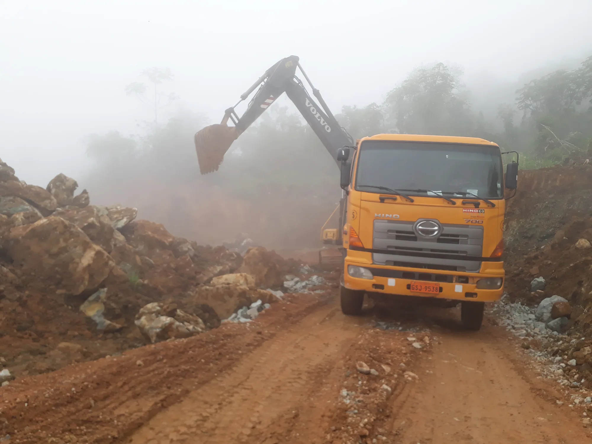 Camión y excavadora cargando material en el acceso a la concesión